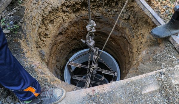 Service workers inspecting a well for sediment.