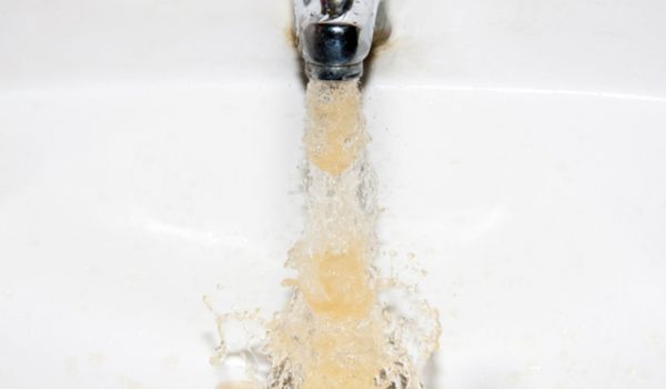 A picture of what yellow water looks like flowing out of a sink faucet