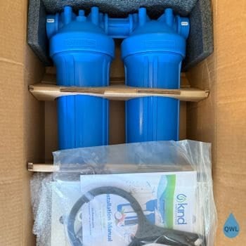 Kind 1000 whole house water filter unboxing showing dual blue housings, installation manual, and included wrench.