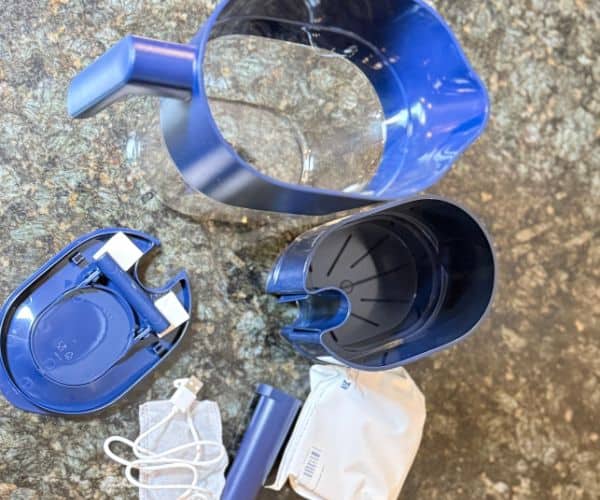 LARQ PureVis water filter pitcher shown disassembled with lid, reservoir, filter cartridge, UV wand, and charging cable on counter