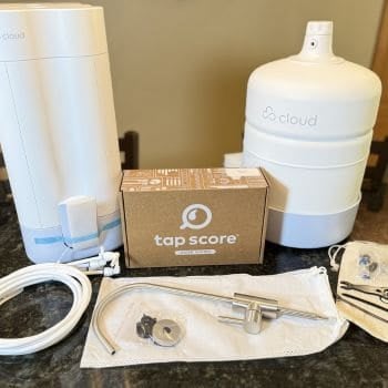 Cloud RO reverse osmosis system unboxed showing filter unit, storage tank, faucet, tubing, hardware, and Tap Score water testing kit