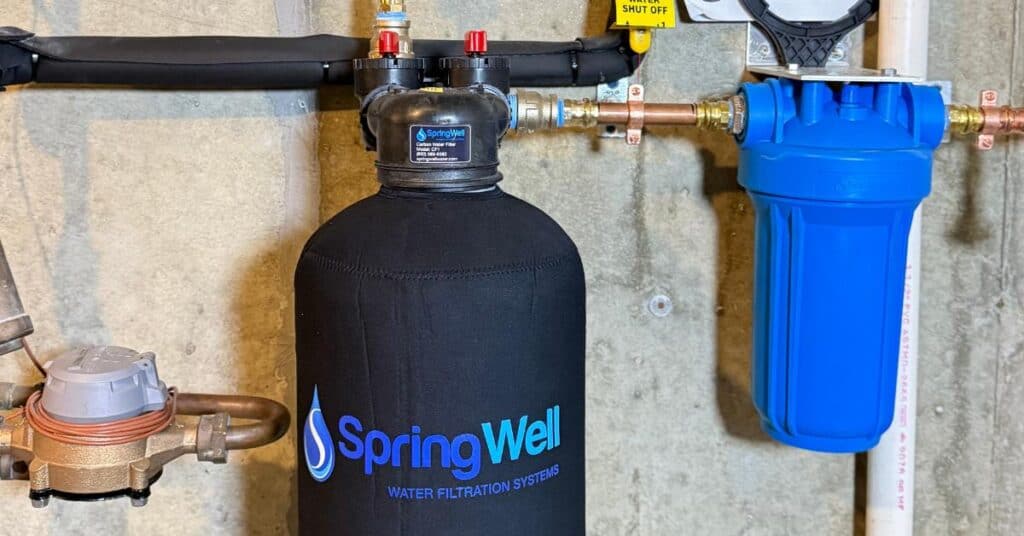 SpringWell CF1 whole house water filter installed in a basement with copper piping and water meter.
