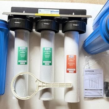 iSpring WGB32B whole house water filter unboxed with three filter cartridges, housings and installation wrench